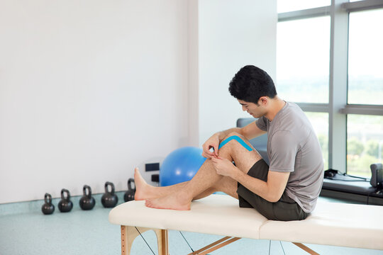 Man Applying Knee Tape in Physical Therapy