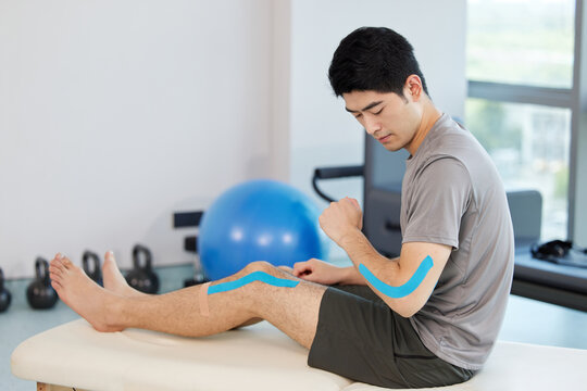 Physical therapy knee taping Asian man