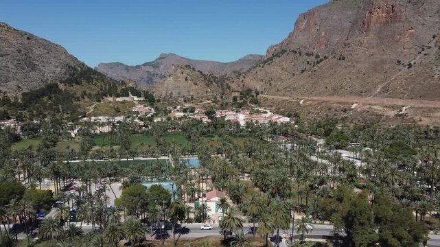 Drone shot of San Anton district in Orihuela surrounded by iconic palm grove and arid mountains.