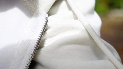 Close-up of a white jacket with visible zipper and soft fabric texture, creating a clean contemporary fashion detail. © Ангелина Снопок
