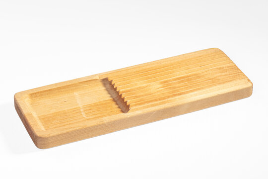 Light wood cheese slicer with grooved surface and angled cutting slot on white background
