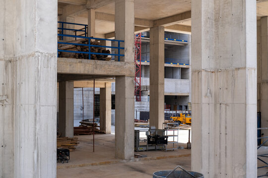Residential real estate construction site with unfinished concrete buildings and a tower crane. Modern urban development and property construction concept.