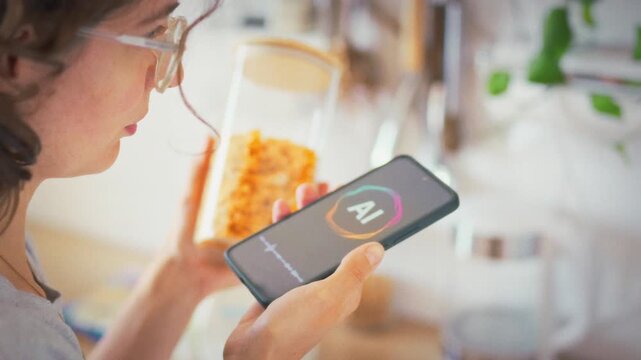 A woman holds a jar of corn flakes and consults an AI voice assistant on her smartphone about nutritional value. Concept of healthy breakfast and smart technology in daily life