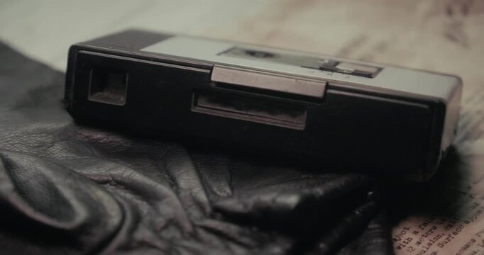 Desktop plan shot reveals a surveillance device, leather gloves and confidential UFO reports, creating a vintage undercover intelligence and mystery storytelling concept.
