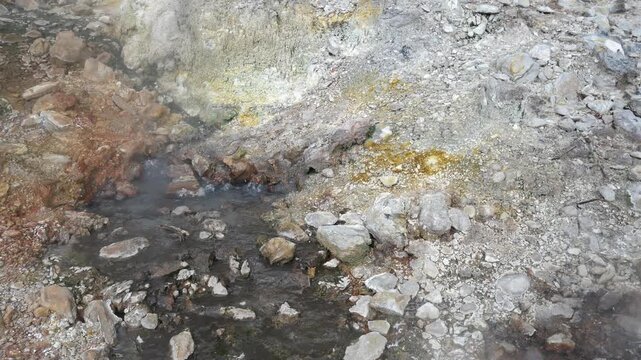 Geothermal springs in Tuscany, Italy, with mineral-rich rocks, steaming ground, and vivid green thermal deposits, showcasing volcanic activity, natural energy, and unusual landscape formations