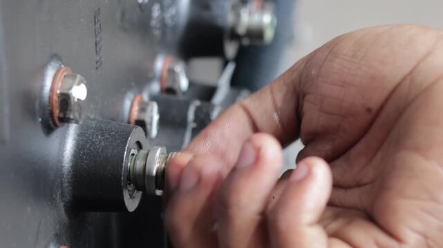 Static shot of mechanic hands installing threaded test point fitting in heavy machinery.