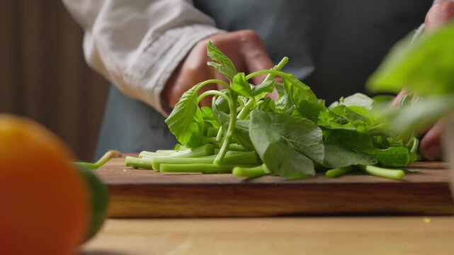 Cutting fresh amaranth greens leaves on a wooden cutting board for cooking