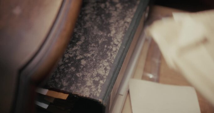 Close-up of a leather-gloved hand placing a brown envelope inside a drawer in dark shadows, evoking secrecy, clandestine activity and espionage.