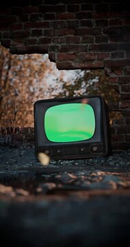 Vintage TV turning on with noise and a green screen mockup in an abandoned post-apocalyptic ruin. Vertical Video