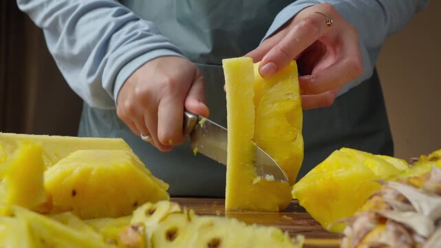 Slicing fresh juicy pineapple with a kitchen knife, in kitchen counter top