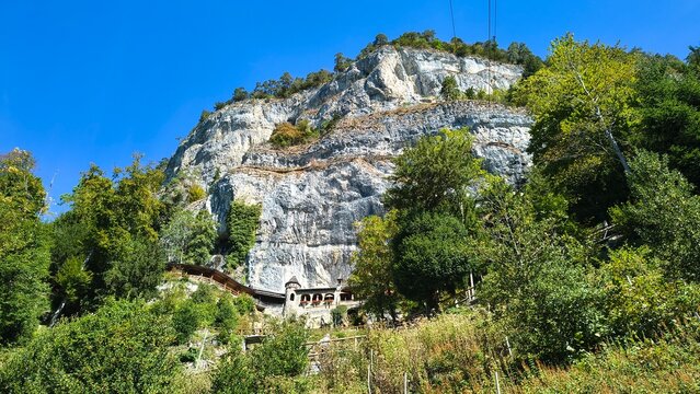 Struttura storica ai piedi di parete rocciosa immersa nel verde