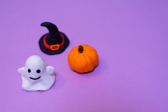 Halloween ghost pumpkin and witch hat on purple background