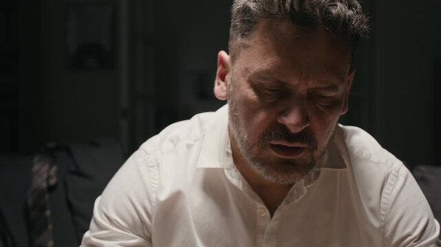 Middle aged Caucasian man examining wedding ring and drinking whiskey in distress. Footage ideal for mental health awareness, addiction recovery campaigns, and divorce counseling videos
