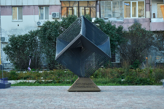 Tyumen, Russia - September 6, 2026: Geometric metal art sculpture named Stability standing in front of residential building in city neighborhood