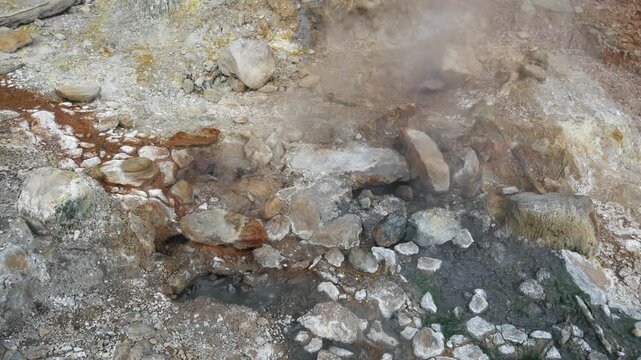 Geothermal springs in Tuscany, Italy, with mineral-rich rocks, steaming ground, and vivid green thermal deposits, showcasing volcanic activity, natural energy, and unusual landscape formations