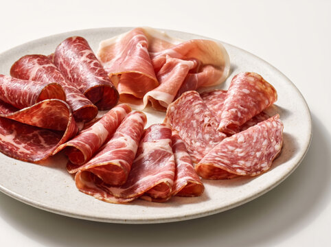 Charcuterie board platter with folded slices of prosciutto, salami, and coppa