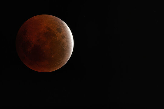 Partial lunar eclipse blood moon with deep copper red shadow and silver crescent off-center rule of thirds editorial astrophotography saros cycle observation