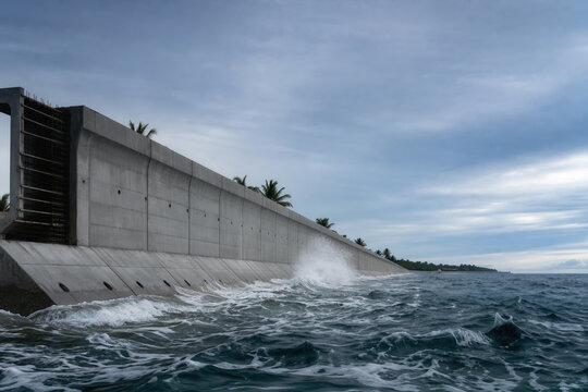 Concrete coastal sea wall protecting low-lying tropical shoreline from ocean surge and coastal flooding sea level rise climate resilience infrastructure barrier