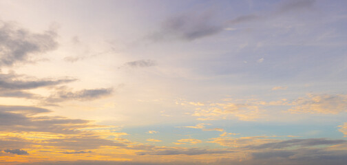 Obraz premium Soft sunset sky with golden glow and pastel purple clouds,A beautiful panoramic view of a soft sunset sky featuring a warm golden glow near the horizon blending into gentle pastel purple and light.