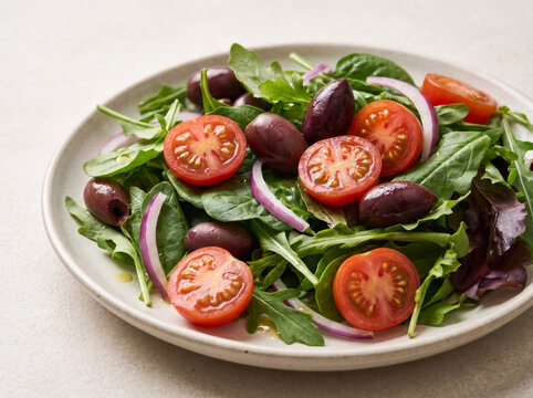 Fresh salad plate with leafy greens, cherry tomatoes, olives, and onion