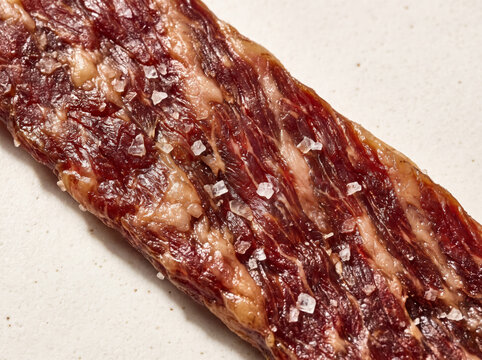Closeup of dry aged cured beef jerky strip sprinkled with coarse salt