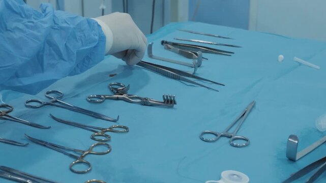Surgical Nurse Hand Reaching for Self-Retaining Retractor on Sterile Table