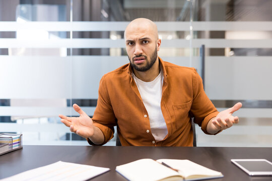 Confused man shrugging during an office meeting