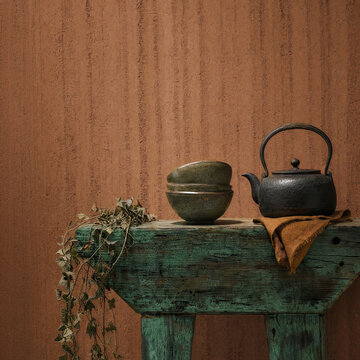 Cast Iron Teapot and Ceramic Bowls on Turquoise Rustic Bench Against Terracotta Wall