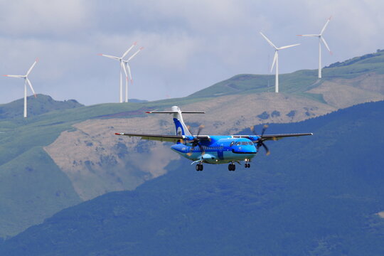 An Amakusa Airlines ATR 42-600 approaches head-on with wind turbines on the ridge behind (JA01AM) on September 3, 2015 in Japan.
