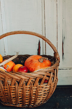 Thanksgiving harvest basket on rustic door porch. Fall pumpkin and fruit crops. November background. Autumn nature aesthetic. Traditional festive holiday. Halloween greeting card