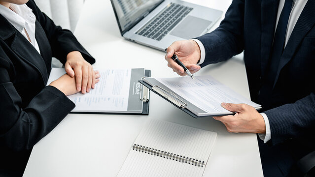 Man employer holding pen to pointing on resume and asking candid