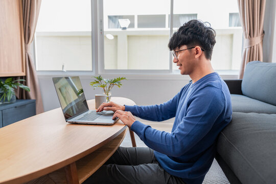 Asian man in casual clothes, typing on laptop about new business