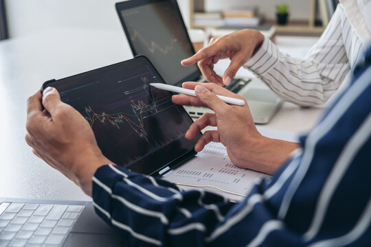 Business trader team are pointing at statistics graph on tablet