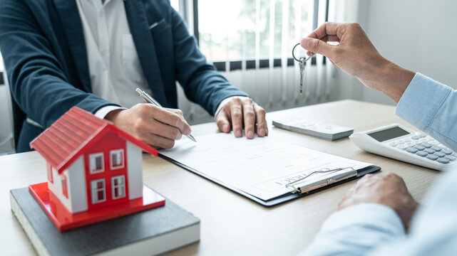 Real estate broker agent holding filing keys to the customer after signing rental lease contract of the sale purchase agreement
