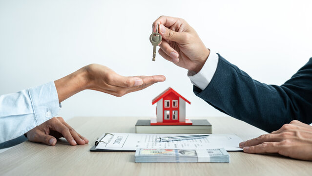 Real estate broker agent holding filing keys to the customer after signing rental lease contract of the sale purchase agreement