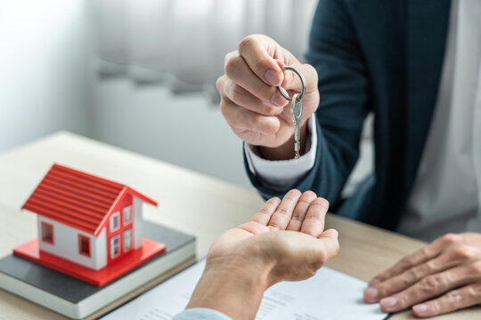 Real estate broker agent holding filing keys to the customer after signing rental lease contract of the sale purchase agreement