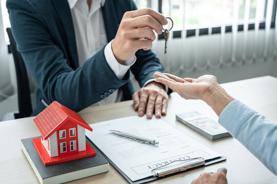 Real estate broker agent holding filing keys to the customer after signing rental lease contract of the sale purchase agreement