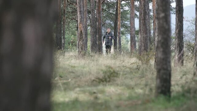 A man is running in a forest wearing a plaid jacket, slow motion isolated cinematic shot