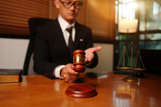 Judge or Lawyer Knocking Wooden Gavel on Sound Block in Office