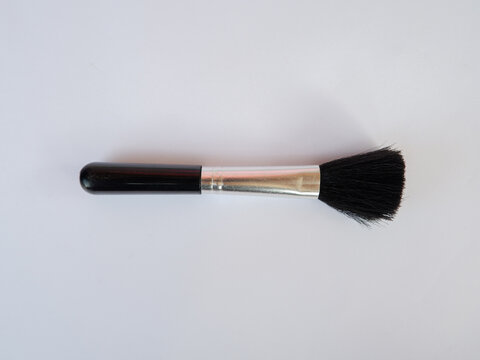 Makeup brush with black handle and soft bristles on plain background for cosmetic application and beauty care design