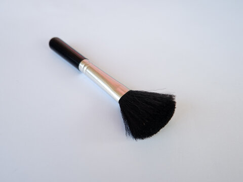 Makeup brush with black handle and soft bristles on plain background for cosmetic application and beauty care design