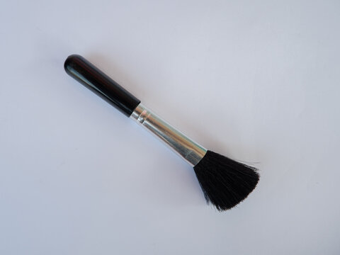 Makeup brush with black handle and soft bristles on plain background for cosmetic application and beauty care design