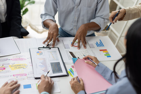 Business people discussing charts and graphs, working together on project strategy and planning in office.