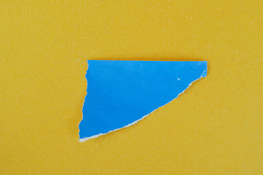 Torn Blue Paper Piece with Ripped Edge on Yellow Textured Background for Copy Space Design Banner Poster Collage