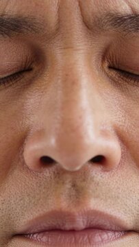 Vertical video: Starting with closed eyes male face showing small furrow mouth parting in studio