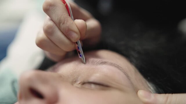 A woman is getting her eyebrows waxed lying on the bed