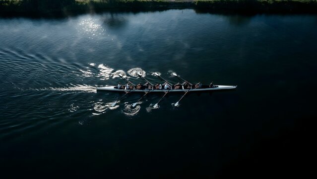 Long Rowing Boat with Multiple Passengers Gliding on Calm Lake Surface at Dawn