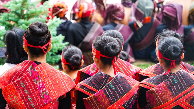 Group of Batak people wearing traditional red and black ulos clothing standing closely together during a local cultural celebration event