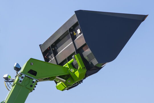 Excavator or bulldozer shovel on blue sky background. Part of industrial machine. Technology