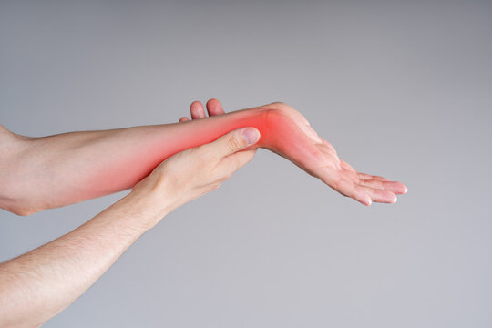 Close up of man massaging painful left arm with red highlighted spot, inflammation of wrist joint, carpal tunnel syndrome medical concept